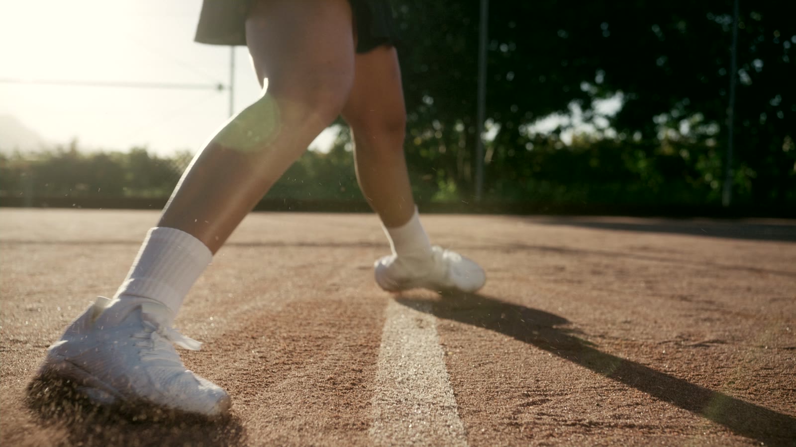 A tennis player plants a foot during a slide on clay